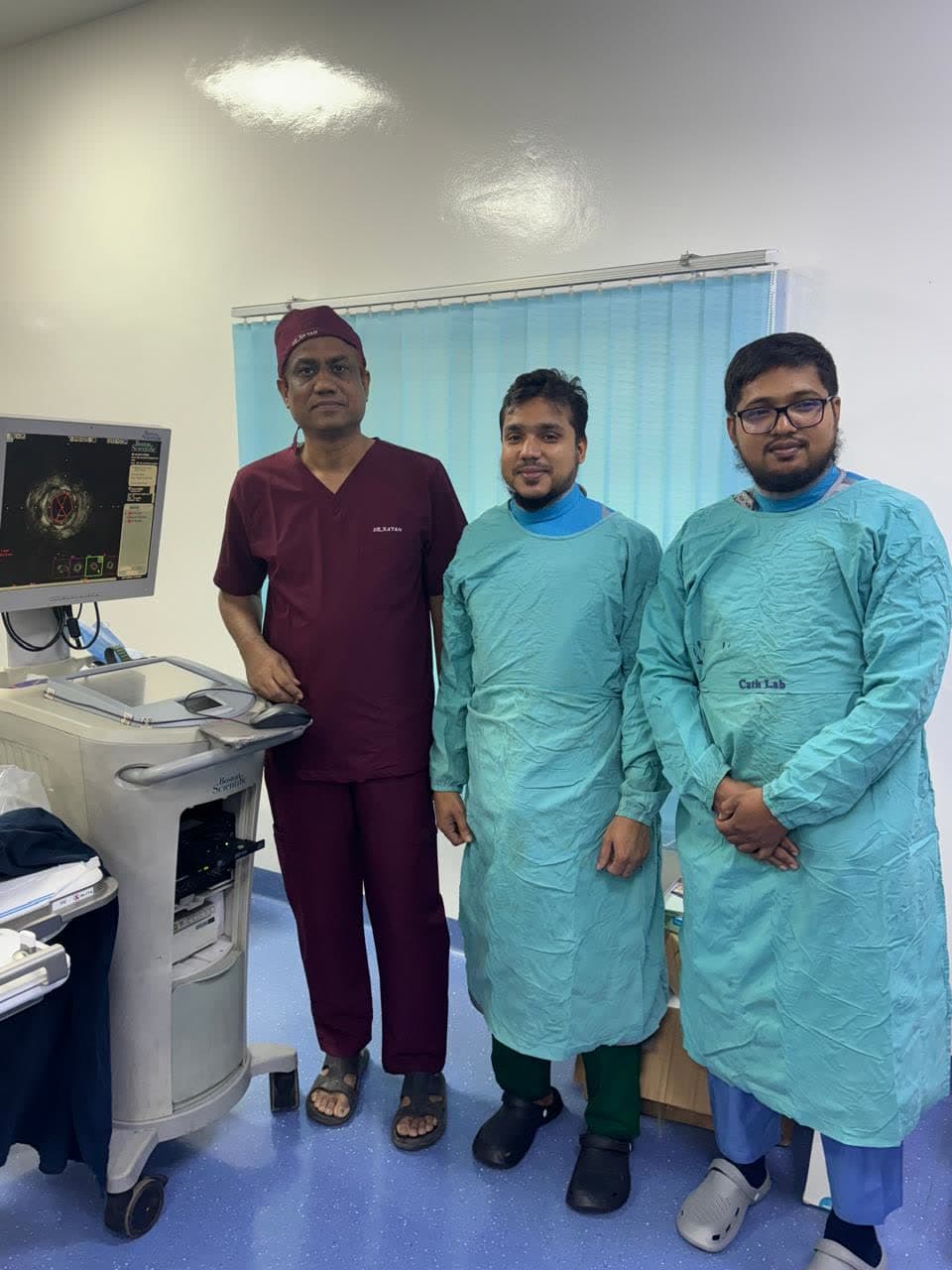 Dr. Md. Shariful Islam with colleagues beside intravascular imaging equipment in the cath lab